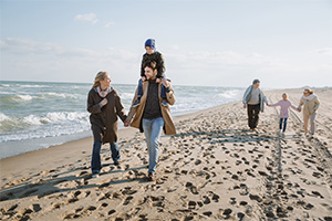 Family walking along the beach wearing winter clothing highlighting year-round living in Ortley Beach real estate