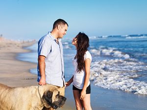 Couple and their large dog enjoying the outdoors lifestyle on the beach afforded by homes for sale in Ortley Beach