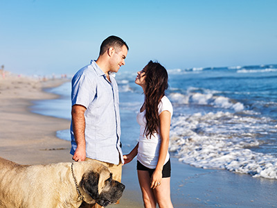 Couple and their large dog enjoying the outdoors lifestyle on the beach afforded by homes for sale in Ortley Beach